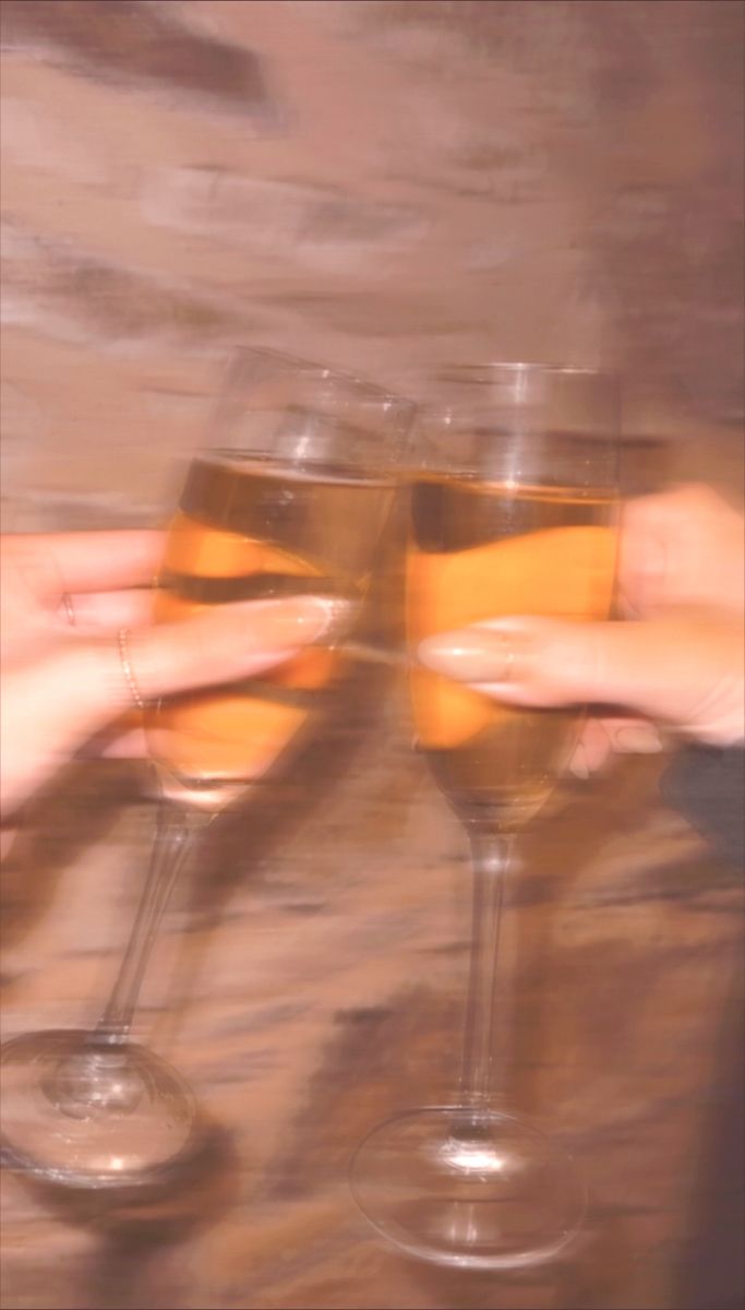 two hands holding glasses with wine in them