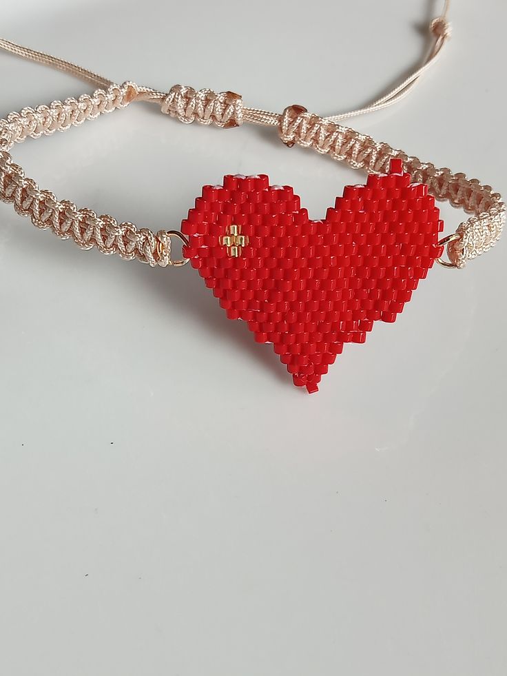 a red heart shaped beaded bracelet on a white surface