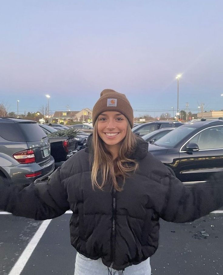 a woman standing in a parking lot holding her arms out to the side and smiling