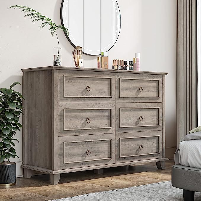 a bedroom scene with focus on the dresser and large mirror over it's top