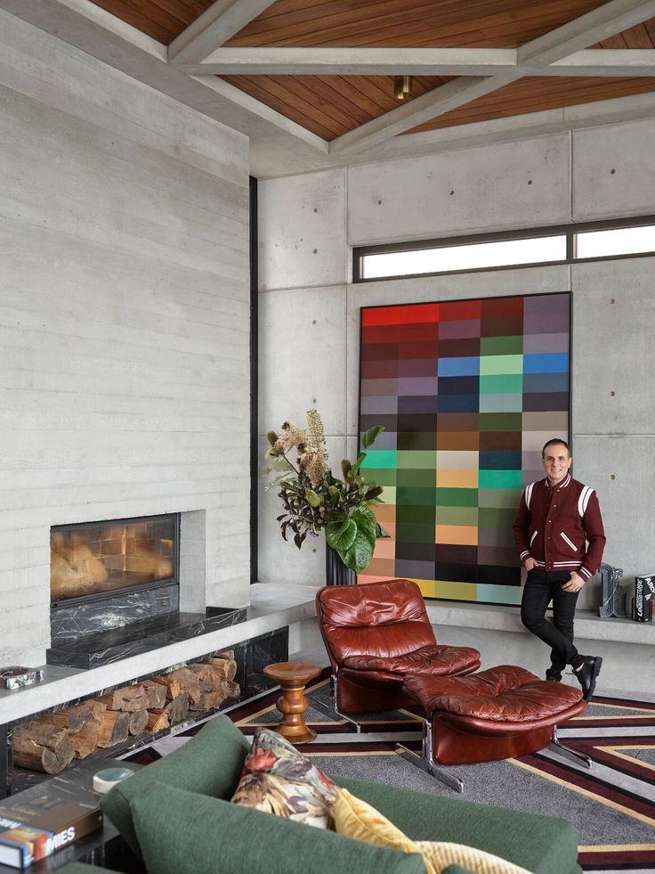 a man sitting in a living room next to a fire place and painting on the wall