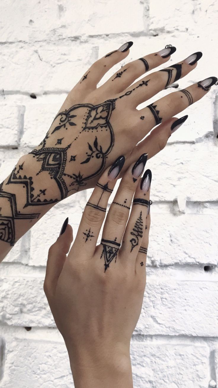 two hands with black and white tattoos on them