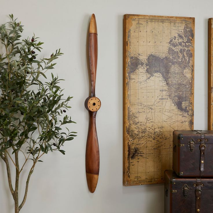 a wooden clock is hanging on the wall next to suitcases and a potted plant