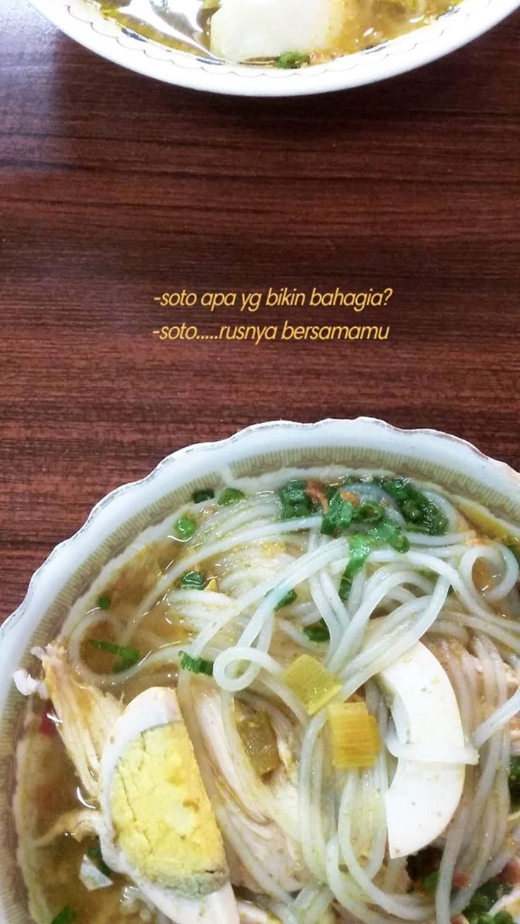 two bowls filled with noodles and vegetables on top of a wooden table next to each other