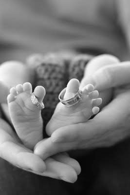 two hands holding a baby's feet in the palm of their mother and father