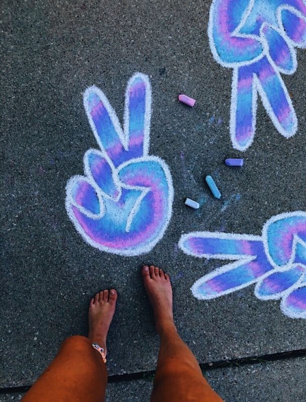 someone is standing on the sidewalk with their feet in front of some chalk drawings and crayons