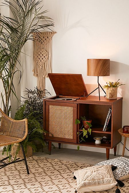 a living room with plants and a record player on the shelf next to a chair