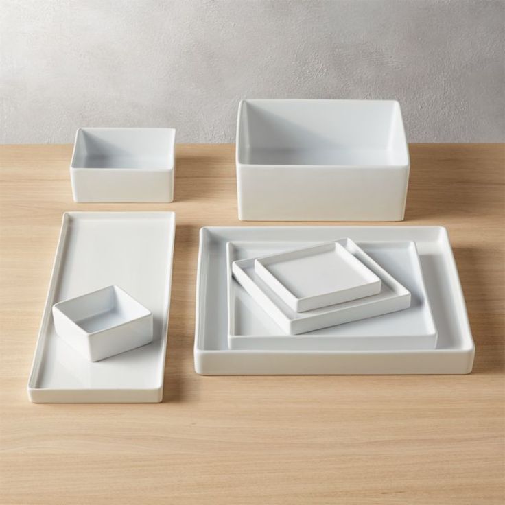 four white square dishes on a wooden table