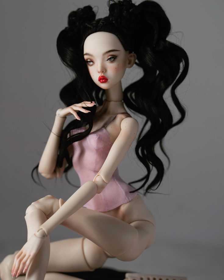 a doll sitting on the ground with her legs crossed