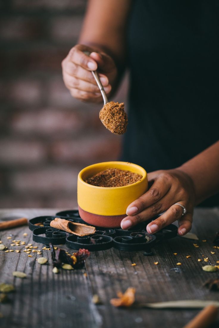 a woman is spooning some food out of a yellow bowl on top of a wooden table