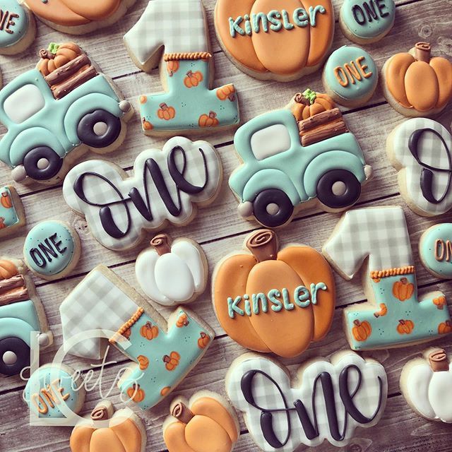 decorated cookies are arranged in the shape of trucks, pumpkins and other items on a table