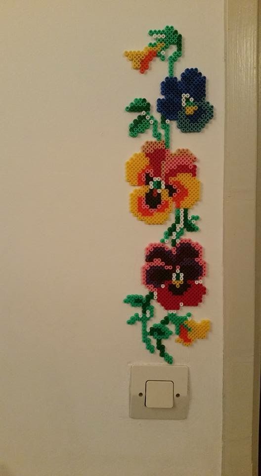 a cross stitch flower design on the side of a white door with a light switch