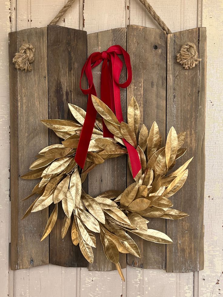 a wooden sign with a red ribbon hanging from it's side and a wreath on the front