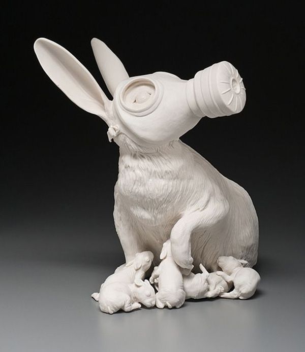 a white ceramic rabbit figurine with a bottle on its back and ears sticking out