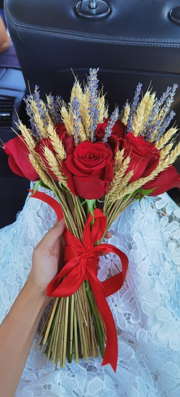 a person holding flowers in their hand on the back seat of a car with red ribbon