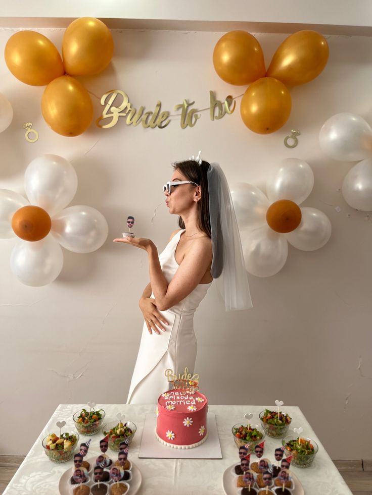 a woman standing in front of a table with cake and cupcakes