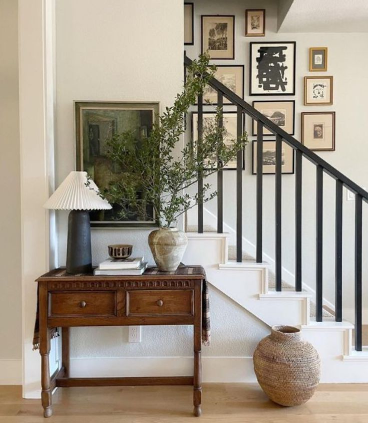 there is a table with a vase on it next to the stairs in this house