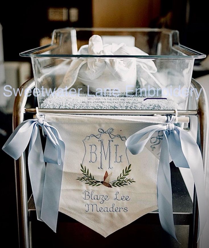 a clear basket filled with lots of white items on top of a metal cart covered in blue ribbon