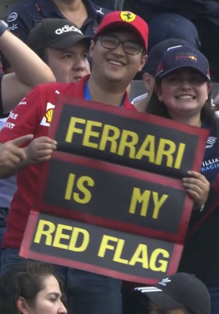 some people are holding up signs in front of the stands at a sporting event that says ferrari is my red flag