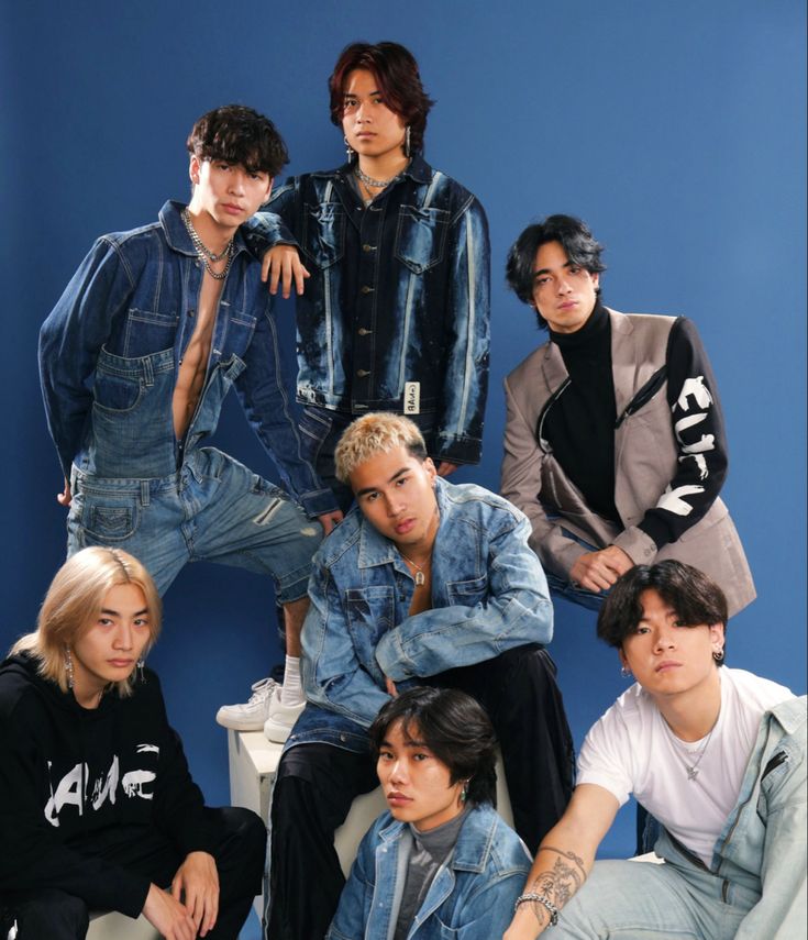 the group of young men are posing for a photo in front of a blue wall