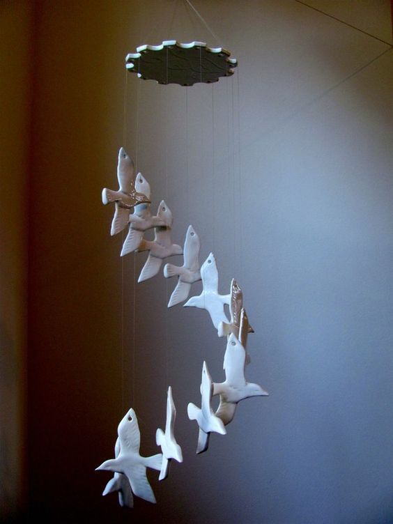 a group of birds flying through the air next to a light fixture in a room