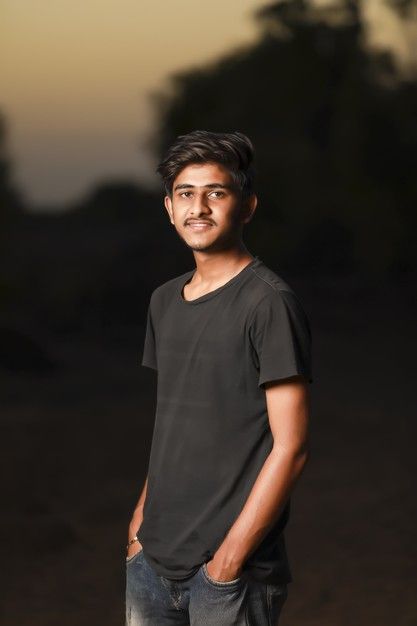 a man standing with his hands in his pockets and looking at the camera while wearing a black t - shirt