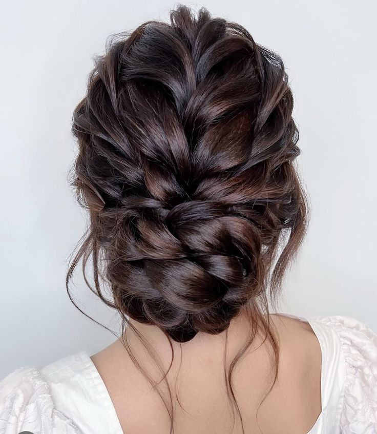 the back of a woman's head with dark brown hair styled into a braid