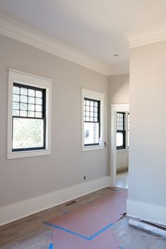 an empty room with two windows and blue tape on the floor