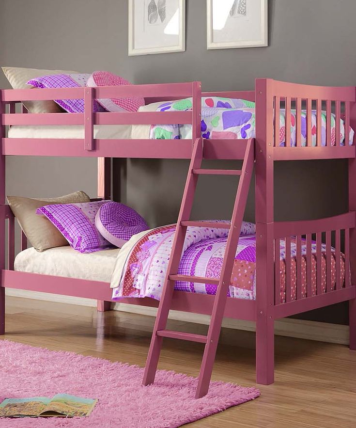 a pink bunk bed sitting on top of a wooden floor next to a purple rug