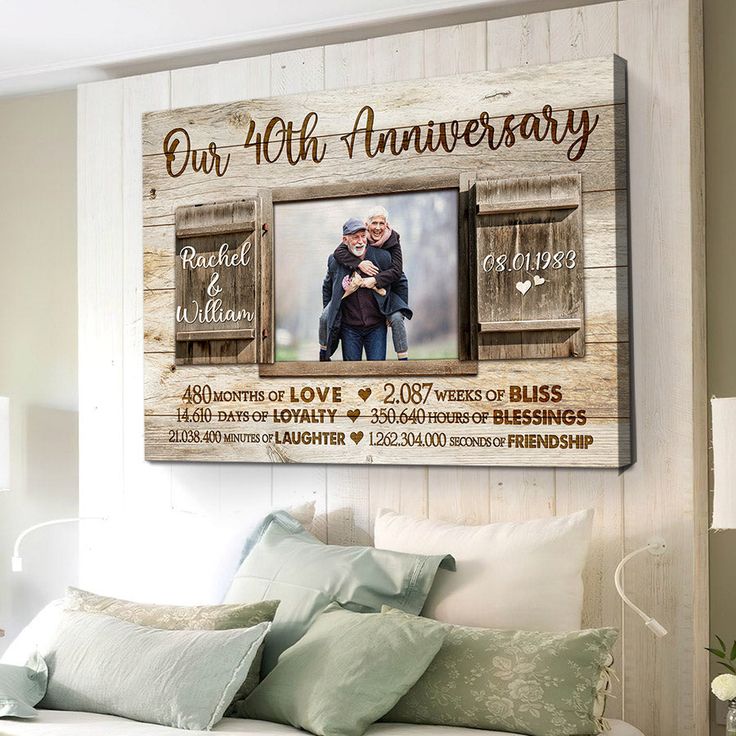 a bedroom with a white bed and a wooden frame on the wall that says our anniversary