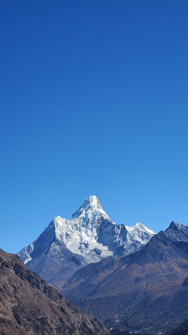 the mountains are covered in snow and brown grass, under a blue sky with no clouds