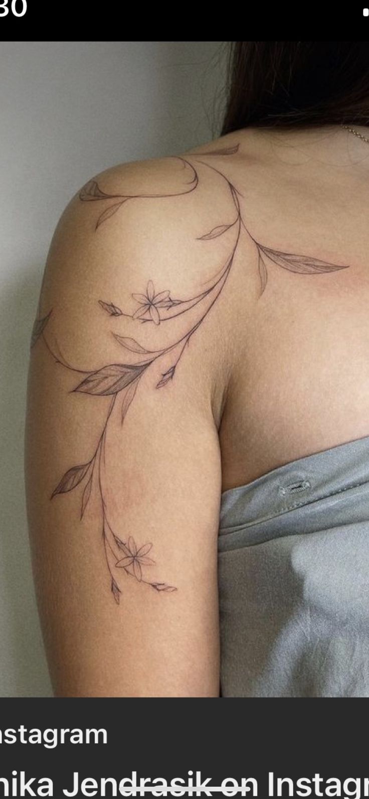 the back of a woman's shoulder with flowers and leaves tattooed on her arm