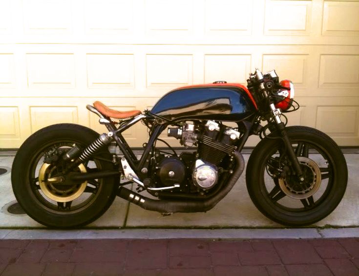 a blue and red motorcycle parked in front of a garage with a white door behind it