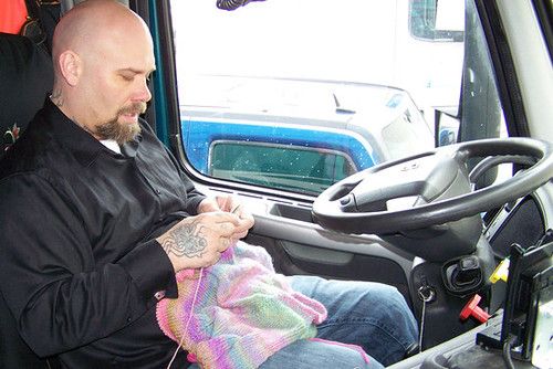 a man sitting in the driver's seat of a truck while holding a baby