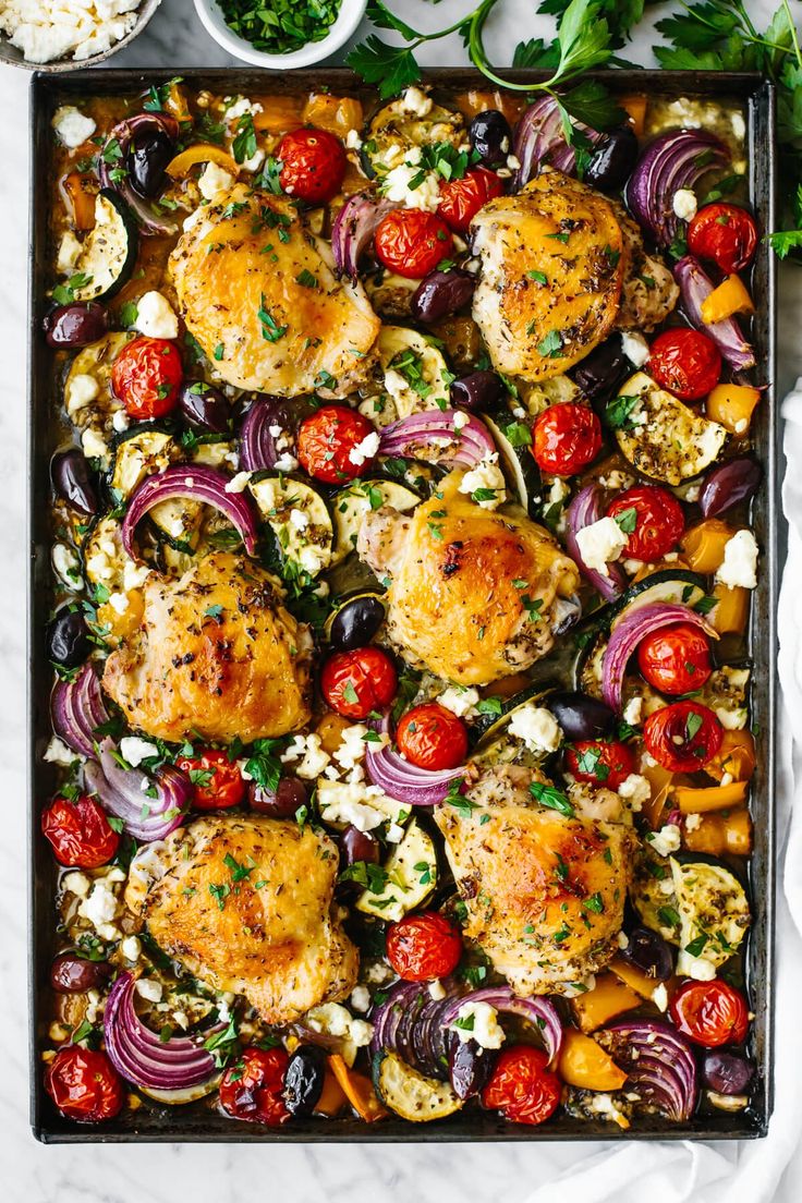 an overhead shot of chicken, tomatoes, onions and feta cheese on a baking sheet