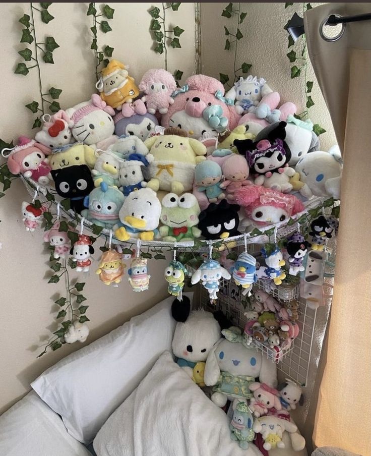 a bunch of stuffed animals are hanging from the ceiling above a bed with white sheets