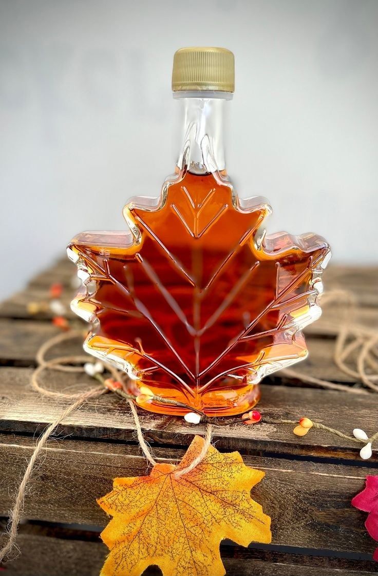 a maple leaf shaped bottle sitting on top of a wooden table