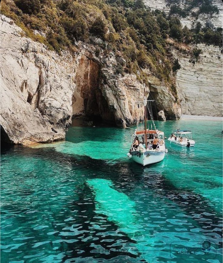 two boats in the water near some cliffs