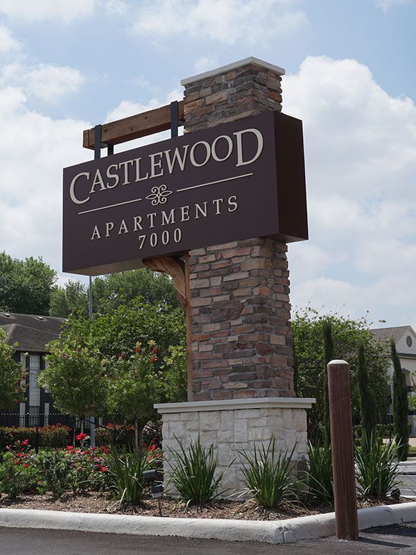 a sign for castlewood apartments in front of some bushes