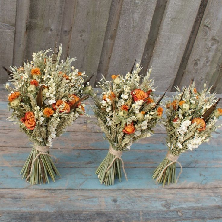 three bouquets of flowers are sitting on a wooden table next to each other and tied with twine