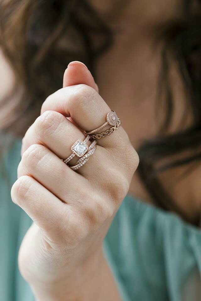 a woman is holding her hand up to the camera with two wedding rings on it