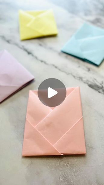 an origami envelope is shown on a marble surface with four different colored envelopes