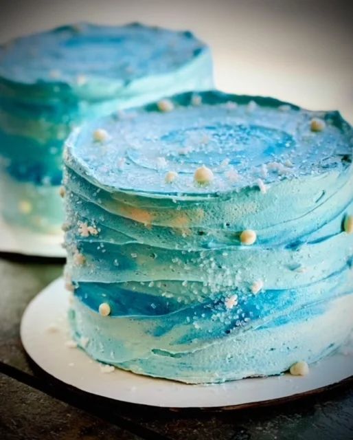 there is a blue cake with white sprinkles on the top and bottom