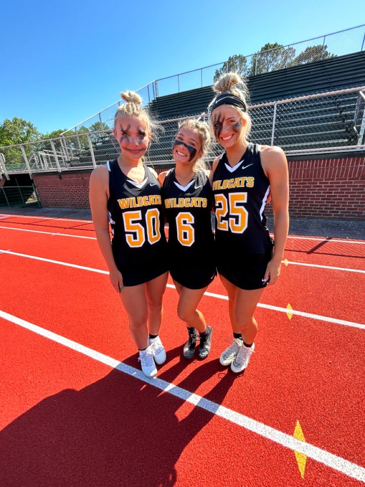 three girls standing on a track with their arms around each other