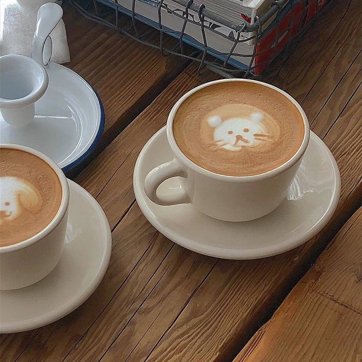 two cups of cappuccino with an animal drawn in the foam on them