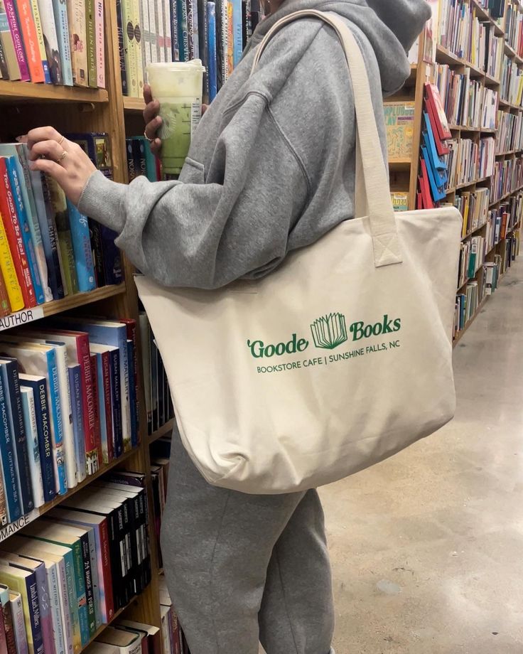 Inspired by our favorite bookstore in Sunshine Falls. Two-sided large zippered tote with Goode Books logo on the one side and the shop design on the other. Bottom Width: 16.5 inDepth 12.5 inStrap Length 24 in Logos Bookstore, Bookstore Logo, Books Logo, Bookstore Cafe, Emily Henry, Debbie Macomber, Book Logo, Book Tote Bag, Zippered Tote