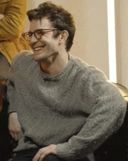 a man sitting on top of a couch next to a woman in a yellow sweater