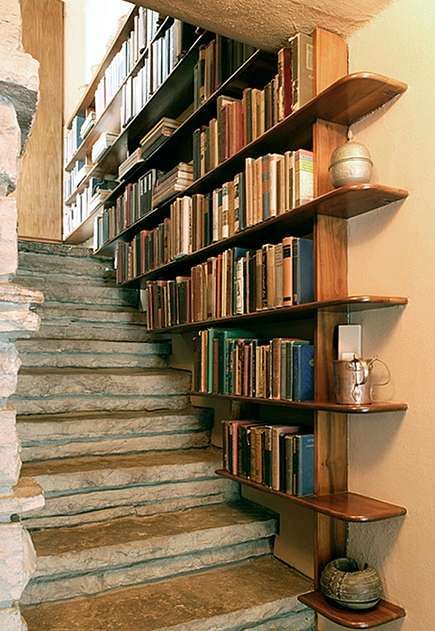 there are many books on the shelves next to the stairs