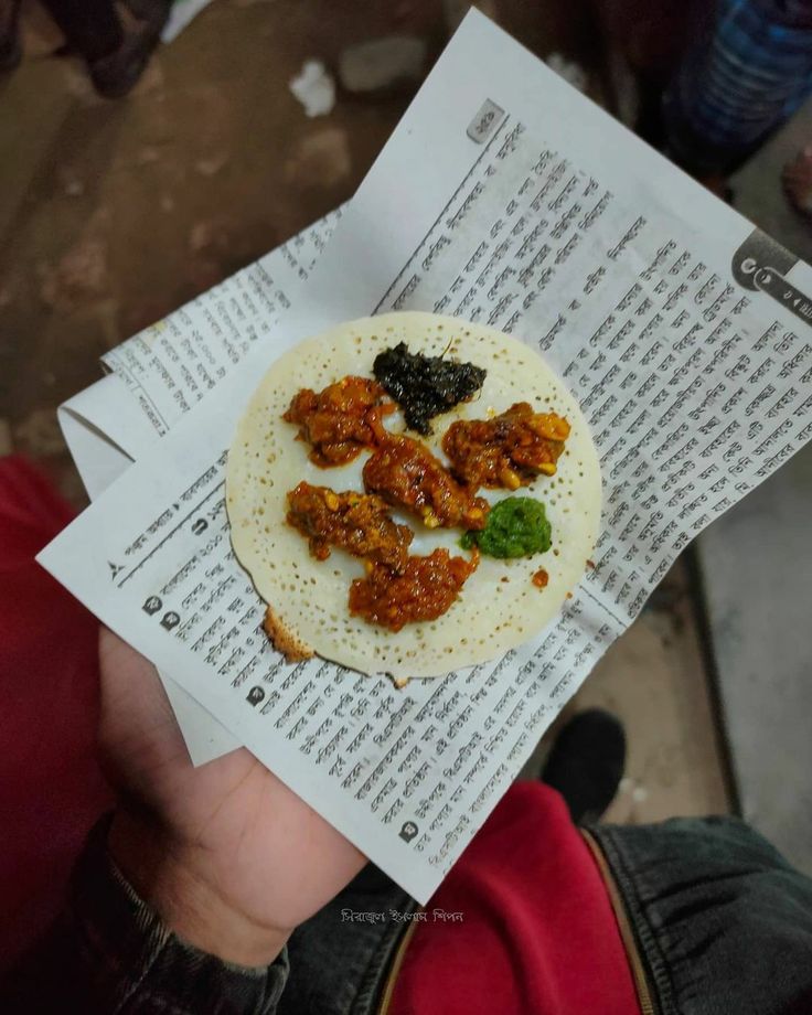 a person holding up a piece of paper with food on it