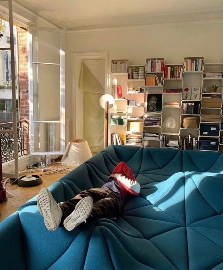 a living room filled with furniture and lots of books on the wall above it is a blue couch